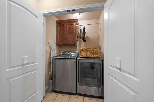 laundry area with cabinets, washing machine and dryer, and light tile patterned floors