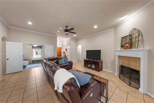 tiled living room with ceiling fan, ornamental molding, and a tiled fireplace