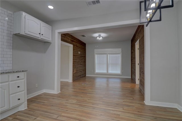 unfurnished dining area featuring light wood-type flooring and wood walls