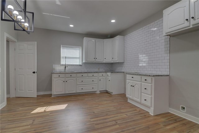 kitchen with white cabinetry, light hardwood / wood-style flooring, and decorative light fixtures