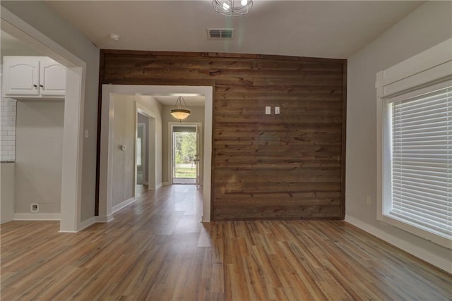 empty room with light hardwood / wood-style flooring and wood walls