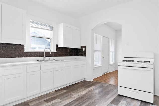 kitchen featuring decorative backsplash, sink, hardwood / wood-style floors, white stove, and white cabinetry