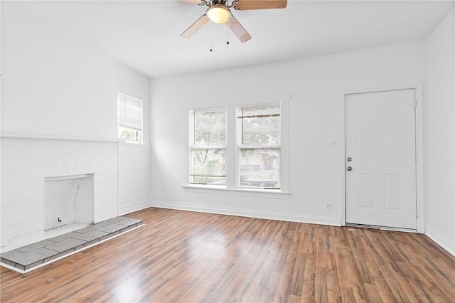 unfurnished living room with a tile fireplace, ceiling fan, and hardwood / wood-style floors