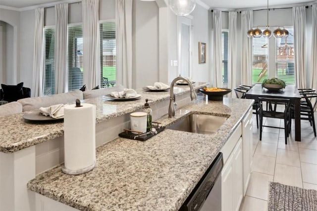 kitchen with crown molding, sink, stainless steel dishwasher, decorative light fixtures, and white cabinetry