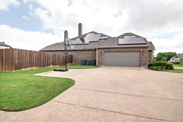 exterior space with solar panels, a garage, central air condition unit, and a front yard