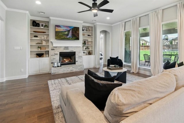 living room featuring hardwood / wood-style floors, a stone fireplace, ceiling fan, and ornamental molding