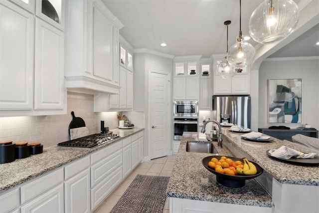 kitchen with appliances with stainless steel finishes, an island with sink, white cabinetry, and sink