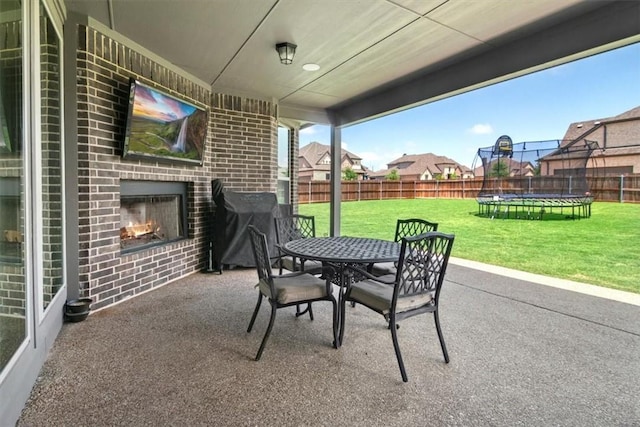 view of patio / terrace with an outdoor brick fireplace and a trampoline