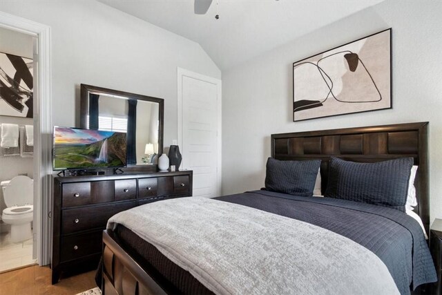 bedroom featuring hardwood / wood-style floors, ceiling fan, lofted ceiling, and ensuite bath