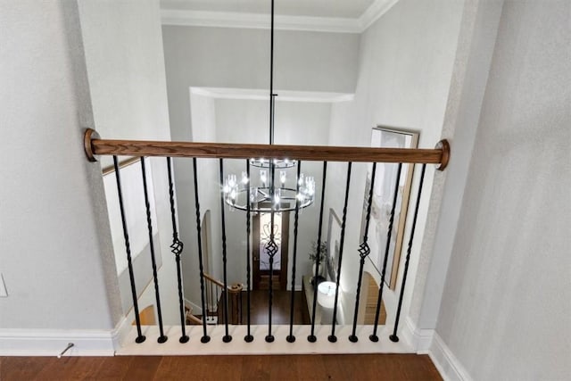 staircase with hardwood / wood-style flooring, ornamental molding, and a chandelier