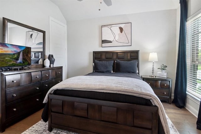 bedroom with ceiling fan, light hardwood / wood-style floors, and vaulted ceiling