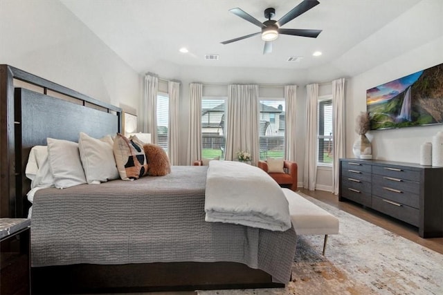 bedroom featuring hardwood / wood-style floors, ceiling fan, and multiple windows