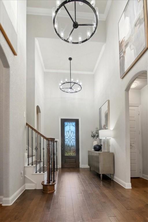 entryway featuring a notable chandelier, dark hardwood / wood-style floors, crown molding, and a high ceiling