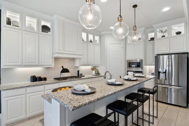 kitchen featuring tasteful backsplash, white cabinetry, a center island with sink, and appliances with stainless steel finishes