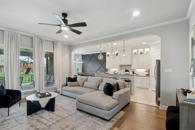 living room with light hardwood / wood-style flooring, ceiling fan, and ornamental molding