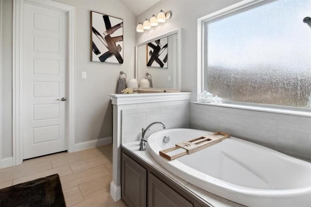 bathroom featuring a tub to relax in, tile patterned floors, and vaulted ceiling