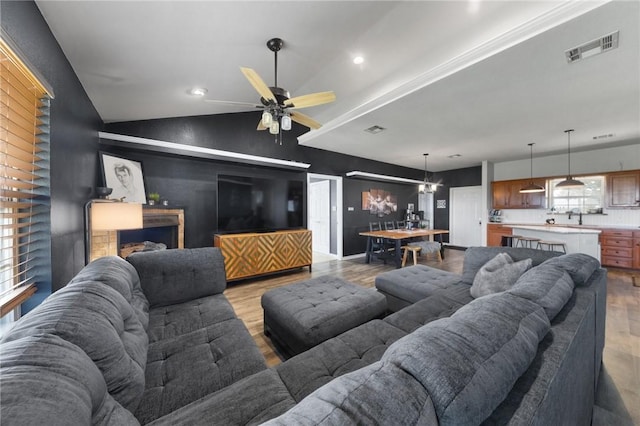 living area with lofted ceiling, visible vents, and light wood-style floors