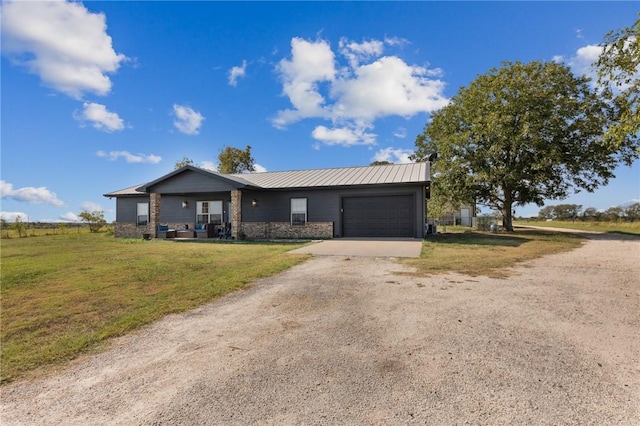 ranch-style home featuring dirt driveway, metal roof, a front yard, and a garage