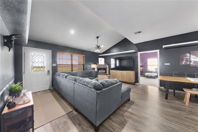 living room with ceiling fan, visible vents, vaulted ceiling, and wood finished floors