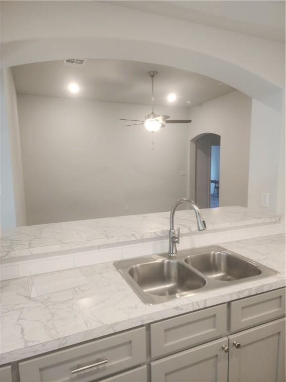 kitchen featuring ceiling fan, gray cabinetry, and sink