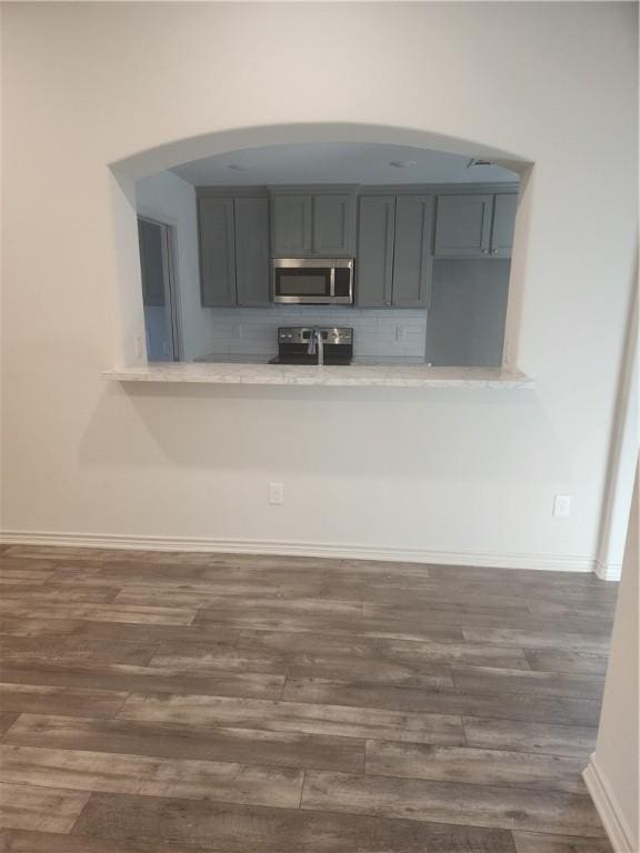 kitchen featuring appliances with stainless steel finishes, dark wood-type flooring, and gray cabinetry