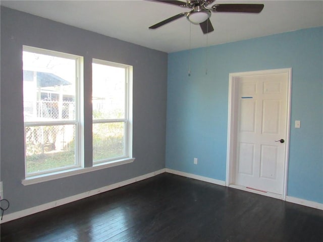 empty room with plenty of natural light, ceiling fan, and dark wood-type flooring