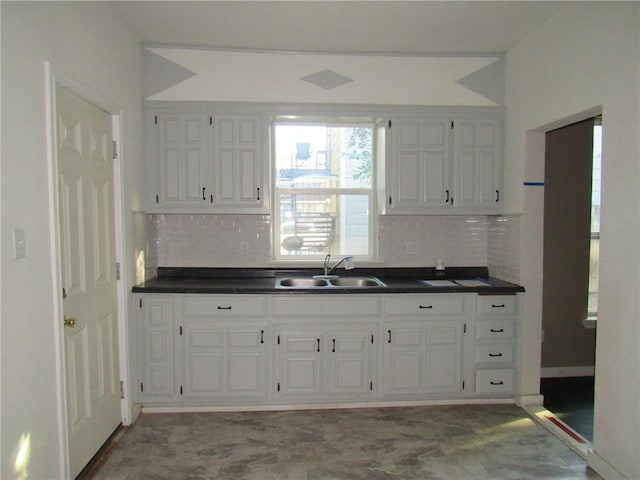 kitchen with white cabinets, decorative backsplash, and sink