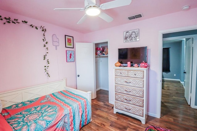 bedroom with baseboards, visible vents, ceiling fan, wood finished floors, and a closet