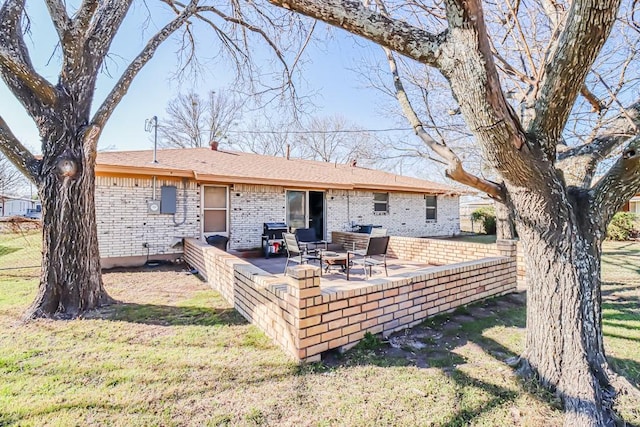 back of house with a patio, brick siding, and a lawn