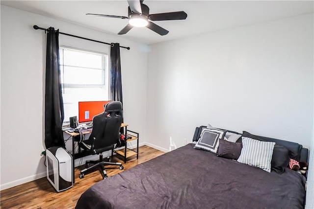 bedroom with ceiling fan, baseboards, and wood finished floors