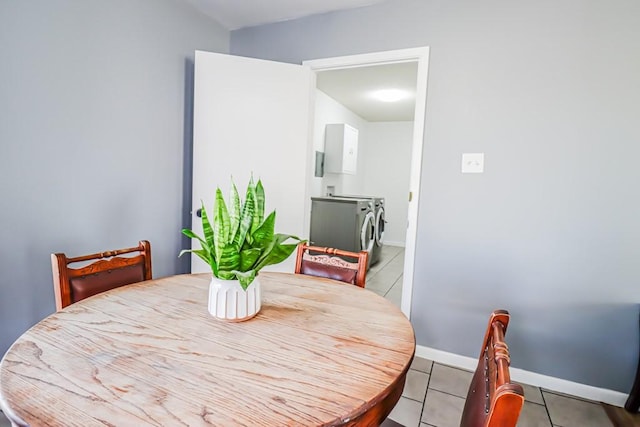 tiled dining space with baseboards and separate washer and dryer