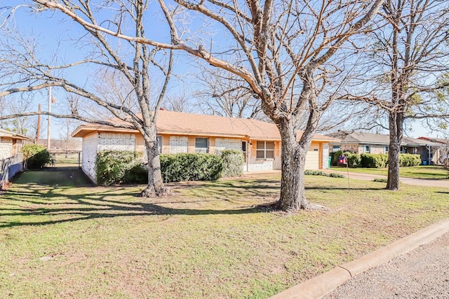 ranch-style house featuring a front yard, brick siding, and an attached garage