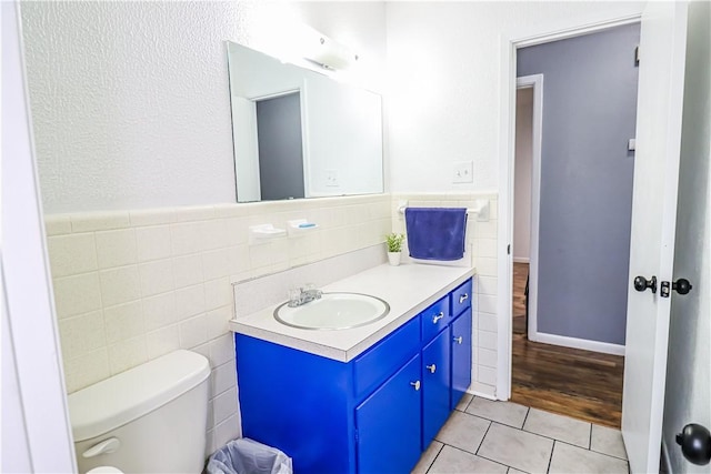 bathroom featuring toilet, vanity, tile patterned flooring, and tile walls