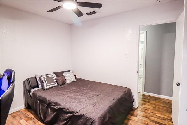 bedroom with baseboards, visible vents, and wood finished floors