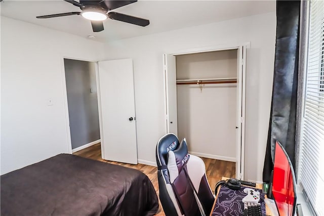 bedroom featuring a ceiling fan, a closet, baseboards, and wood finished floors