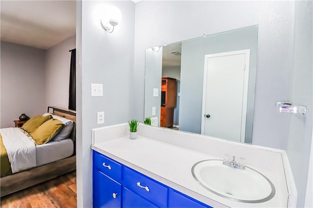 ensuite bathroom featuring ensuite bath, wood finished floors, and vanity