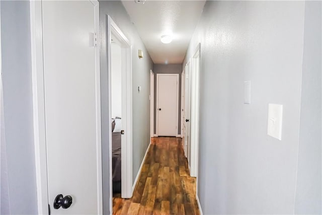 hallway featuring dark wood-style floors and baseboards