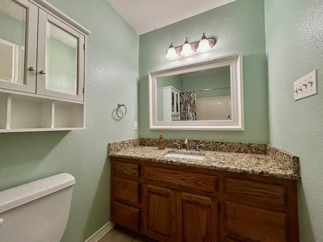 bathroom with walk in shower, vanity, and toilet