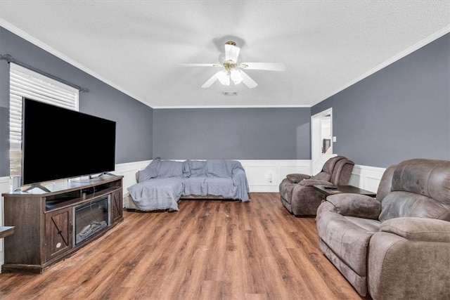 bedroom featuring visible vents, ornamental molding, wood finished floors, wainscoting, and ceiling fan