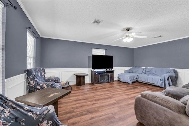 bedroom featuring visible vents, wainscoting, a textured ceiling, and wood finished floors