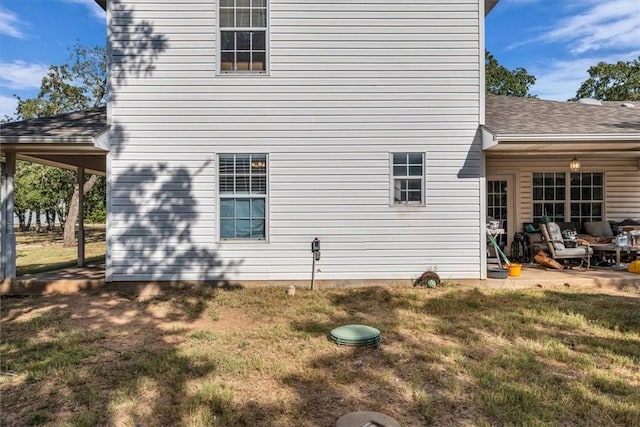 view of side of property featuring a lawn and a shingled roof