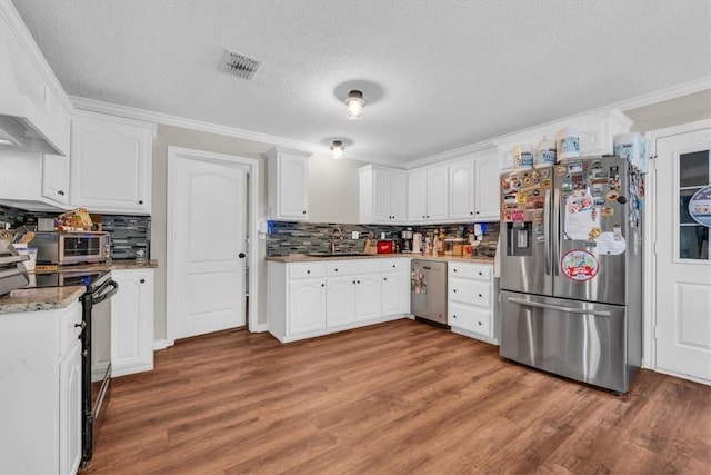 kitchen featuring wood finished floors, visible vents, a sink, ornamental molding, and stainless steel appliances