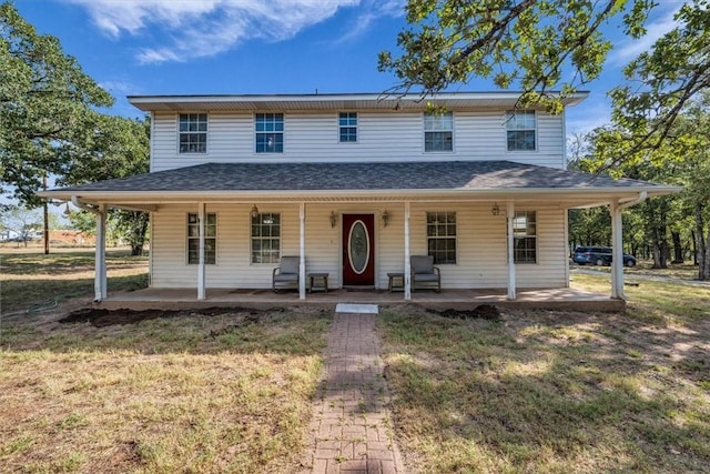 farmhouse with a porch, a front lawn, and roof with shingles