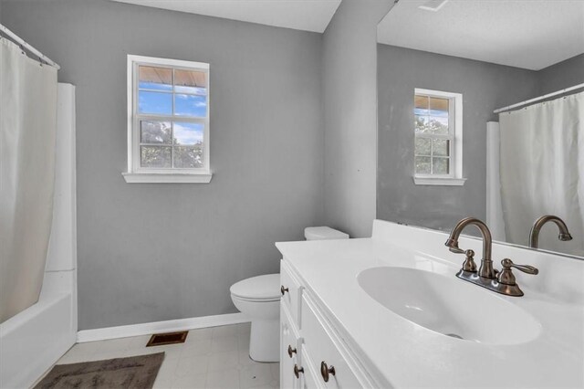 bathroom with vanity, toilet, a healthy amount of sunlight, and baseboards