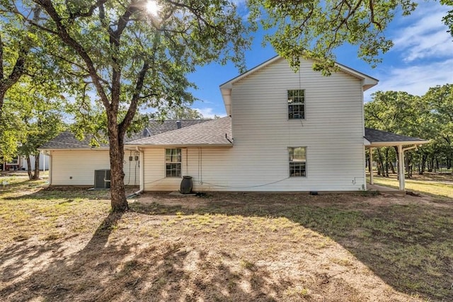 back of house featuring cooling unit, a lawn, and a shingled roof