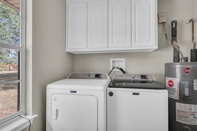 washroom featuring water heater, cabinet space, a wealth of natural light, and separate washer and dryer