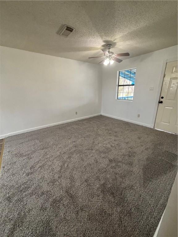 empty room with dark colored carpet, visible vents, a ceiling fan, a textured ceiling, and baseboards