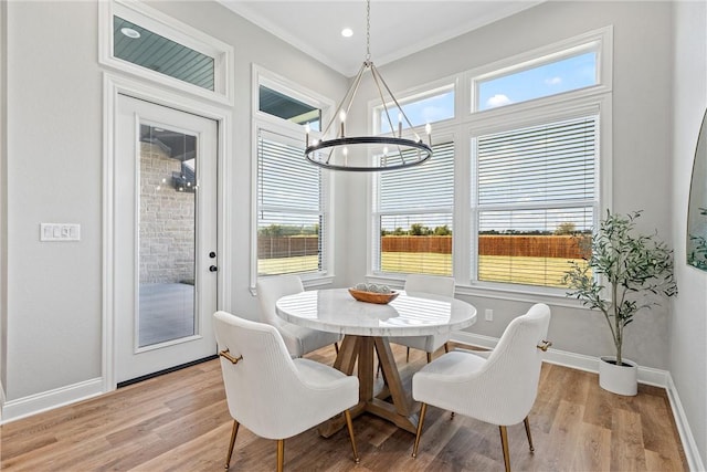 dining space with an inviting chandelier, light hardwood / wood-style flooring, a wealth of natural light, and crown molding