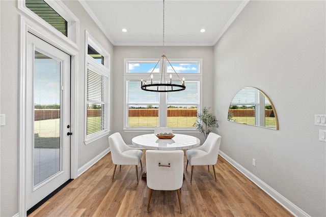 dining space with crown molding, an inviting chandelier, and light wood-type flooring