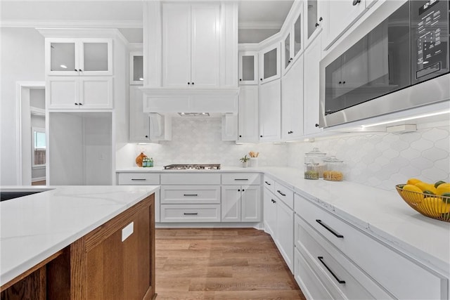 kitchen with light hardwood / wood-style floors, light stone countertops, white cabinetry, and stainless steel appliances